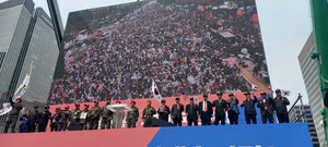 (사진;글로벌GNA) 이승만광장에 모인 수많은 관중(중앙에 태극기를 들고있는 연사가 박웅범고교연합 회장 모습) 